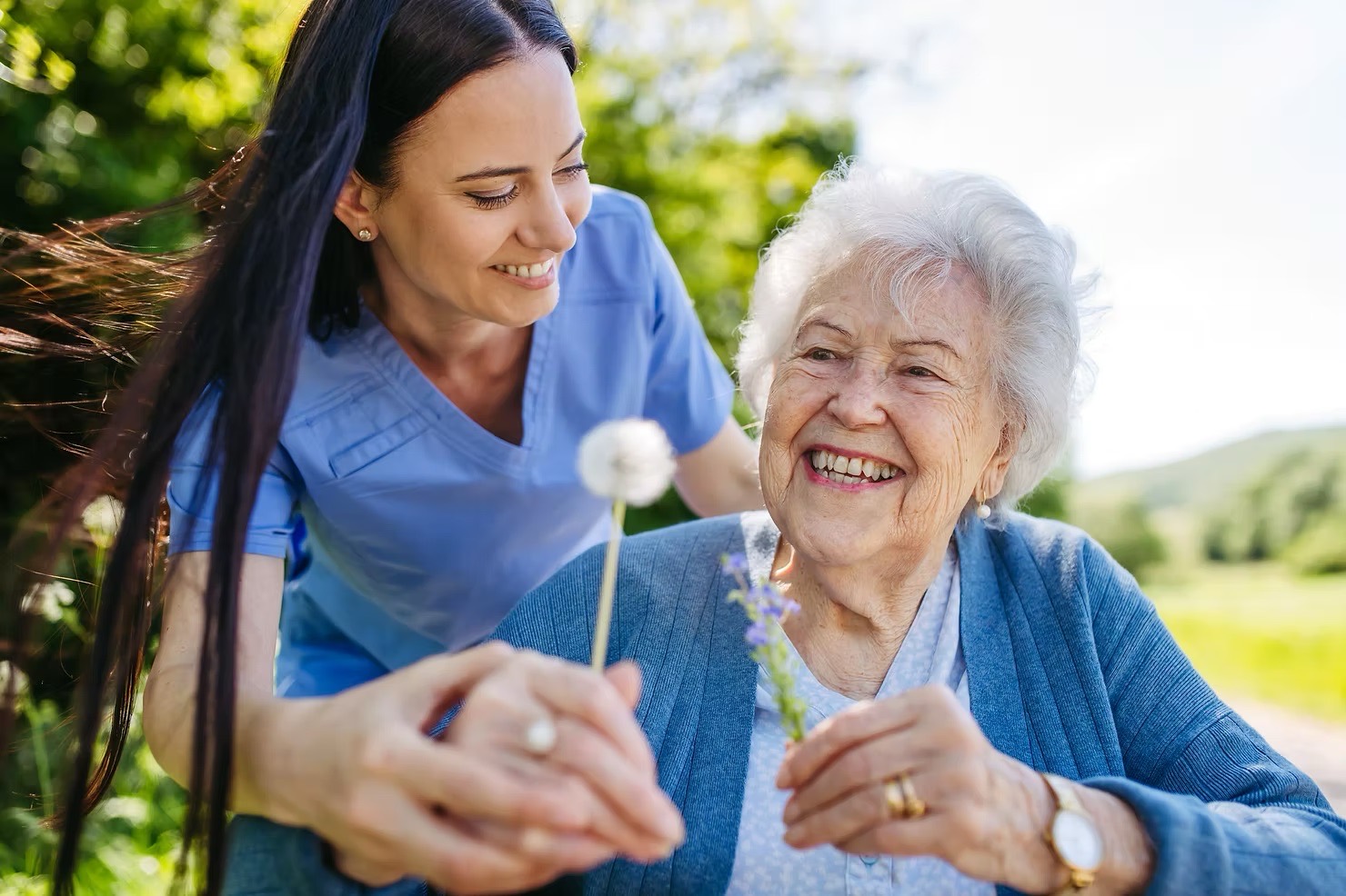 A Horizons caregiver and a participant looking at wildflowers together outdoors