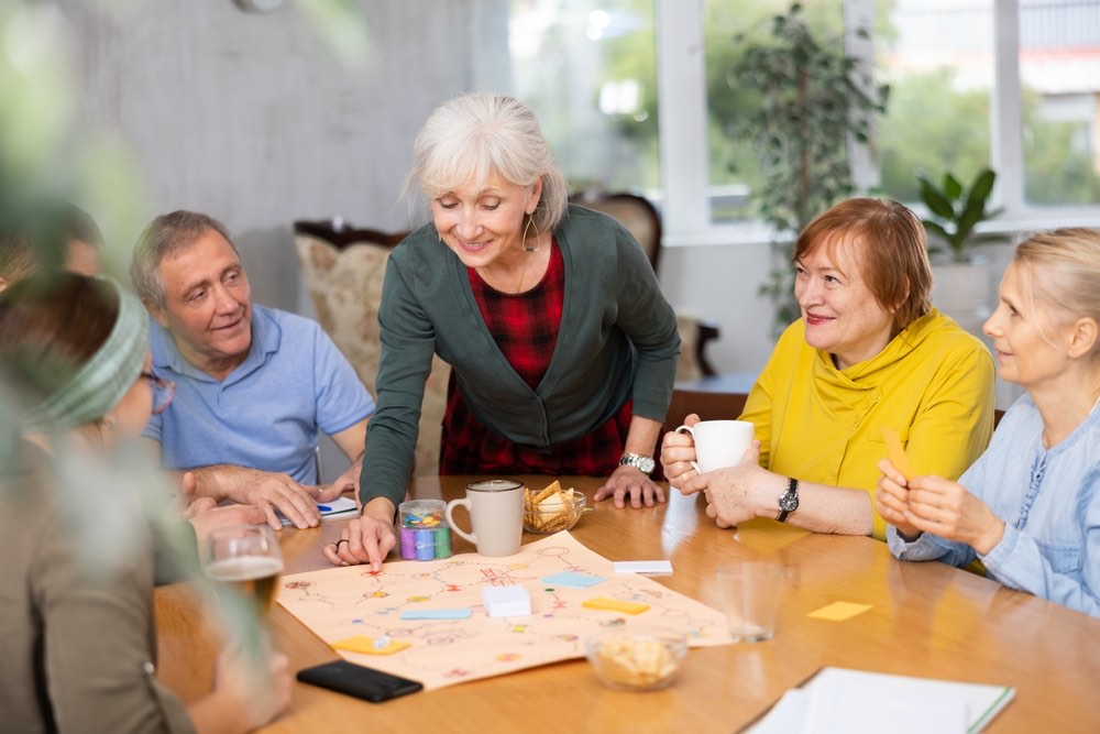 Residents and staff playing a board game together around a table