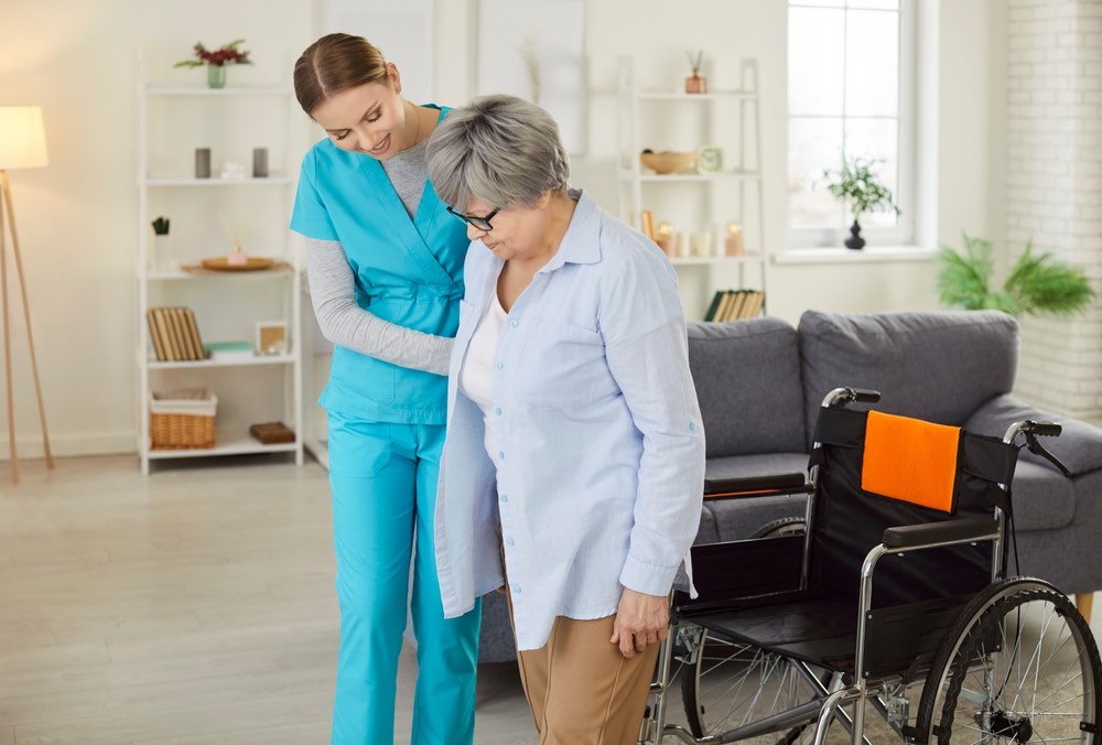 A caregiver supporting a participant as she walks, wheelchair nearby